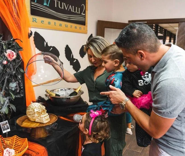 Familia decorando una calabaza en el restaurante Tuvalu 2 de Magic Natura durante Halloween