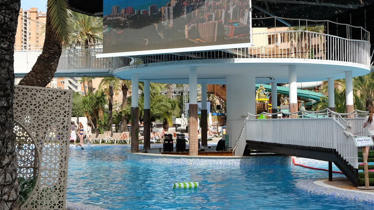Piscina con palmeras y pantalla gigante en Magic World Resort